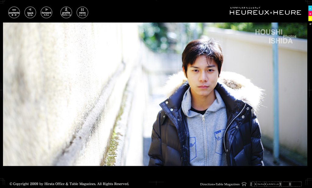 白い壁沿いに立つ石田法嗣のポートレート（第6ページ）